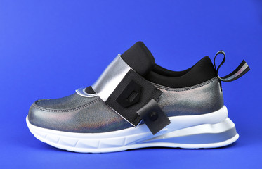 Women's stylish silver sneakers with a white sole on a blue background.