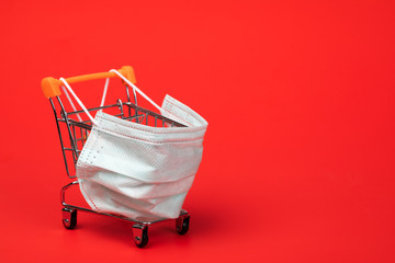 Supermarket cart with protective mask on - shopping during Coronavirus COVID-19 epidemy concept