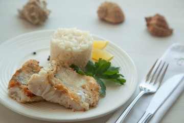Fried pike fish with rice garnish, parsley and lemon