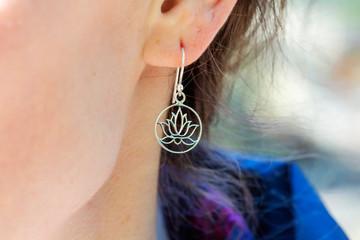 Detail of female ear wearing romantic earring in the shape of lotus