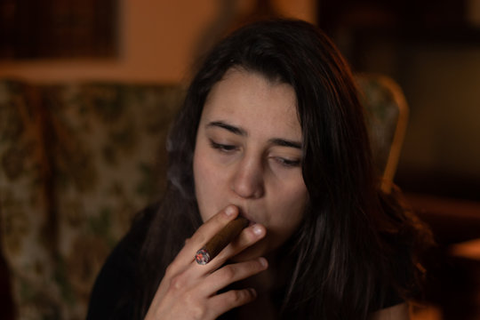 Young woman smoking a large cigar indoors.