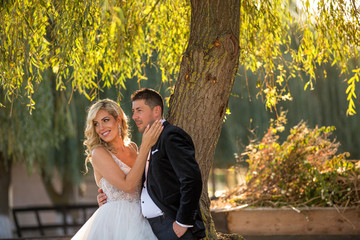 beautiful blonde bride and handsome groom posing outdoor on their wedding day