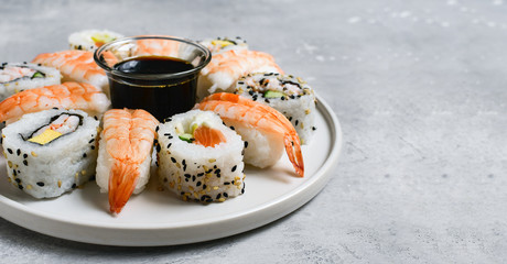 food delivery set of sushi and rolls with salmon and shrimp on a gray table. Top view of sushi, uramaki, hosomaki and nigiri.