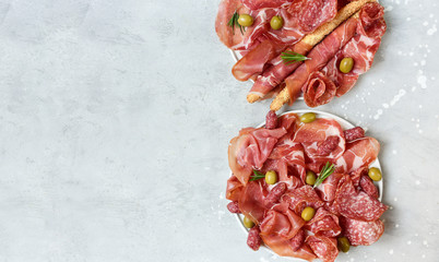 Prosciutto jamon Parma ham salami smoked sausage and olives with grissini breadsticks on a white...