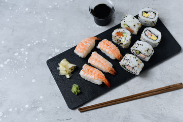 food delivery set of sushi and rolls with salmon and shrimp on a gray table. Top view of sushi, uramaki, hosomaki and nigiri.