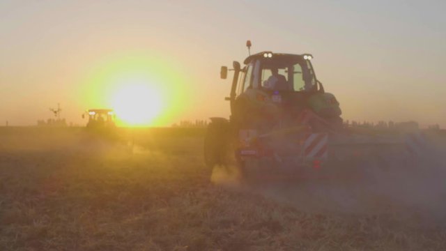 combine harvester working at sunset