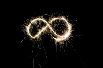 Infinity symbol by light painting with fireworks in isolated natural background. sparks are spreading