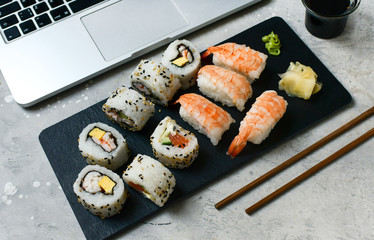 food delivery set of sushi and rolls with salmon and shrimp on a gray table. Top view of sushi, uramaki, hosomaki and nigiri.