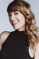 Portrait of a beautiful woman 36 years old with curly hair and an open playful smile and white...