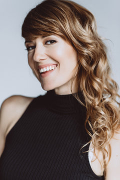 Portrait of a beautiful woman 36 years old with curly hair and an open playful smile and white teeth. Soft selective focus.