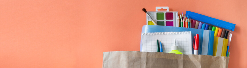 on a coral orange background is a paper bag with colorful stationery for creativity. stationery...
