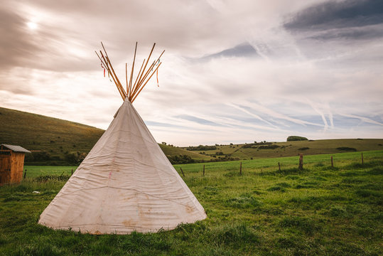 Native American tent on a green field with blue sky 