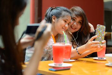 Group of young Asian women as friends taking selfie together outdoors