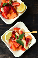 fruit salad with strawberries, yellow melon and banana with lemon. healthy dessert of seasonal fruits. 