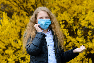 Portrait of sad caucasian child in face mask on closed playground outdoor. Coronavirus social distance quarantine.