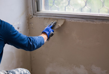 Hand with a spatula, the process of applying a layer of putty. Renovation of apartments. Repair the walls. 
