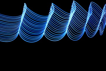 Long exposure photograph of blue neon colour in an abstract swirl, parallel lines pattern against a...