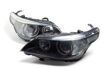 Two xenon headlights for a German auto-optical equipment with a lens and corrector inside on a white isolated background in a photo studio. Spare part for the repair of the front body in the workshop. - obrazy, fototapety, plakaty