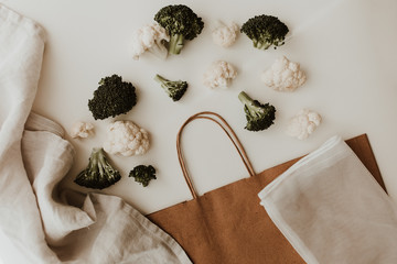 Fresh broccoli and cauliflower spilling from a recycled paper bag – eco-friendly flat lay food...