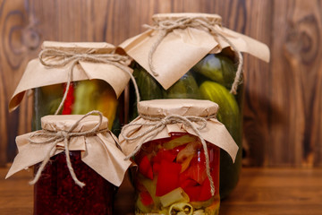 Jar of raspberry jam with canned jars of vegetables on a wooden background. Preserves. - 342407896