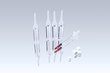 glass ampoules with medicine, syringe and pills are reflected in a mirror surface
