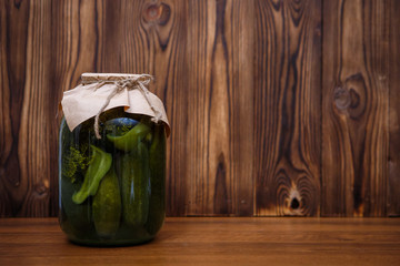 Canned vegetables in glass jars on a wooden background. Pickles. Pickled cucumbers and peppers.