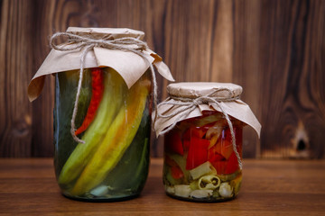 Canned vegetables in glass jars on a wooden background. Pickles. Pickled cucumbers and peppers. - 342409275