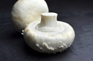 Champignon mushrooms on black background. Vegan food concept. Closeup view.