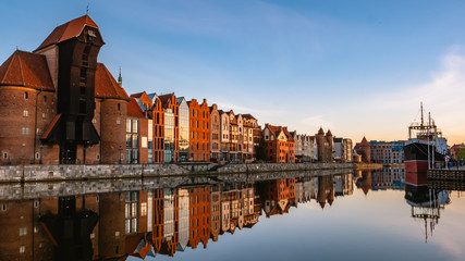 Naklejka premium View of city Gdansk at sunrise. The oldest medival port crane (called Zuraw) and a promenade along the riverbank of Motlawa River. 