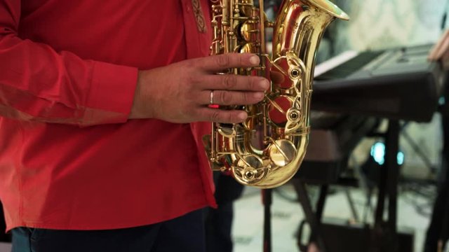 A man in a red shirt plays the saxophone in a restaurant on a holiday