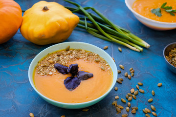 pumpkin soup with purple Basil on a blue background. Top View