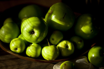Green organic healthy apples in bowl on wooden board. Healthy food