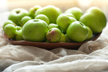 Green organic healthy apples in bowl on wooden board. Healthy food