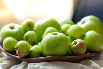 Green organic healthy apples in bowl on wooden board. Healthy food