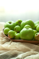 Green organic healthy apples in bowl on wooden board. Healthy food