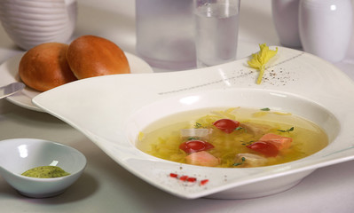 transparent salmon soup with potatoes and red tomato