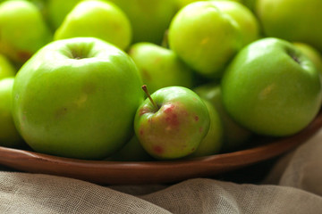 Green organic healthy apples in bowl on wooden board. Healthy food
