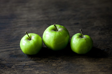 Green organic healthy apples in bowl on wooden board. Healthy food