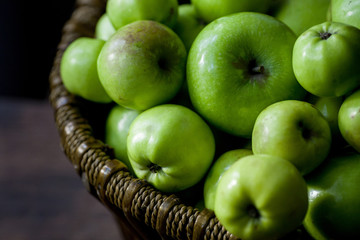 Green organic healthy apples in bowl on wooden board. Healthy food