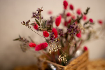 Branches bright pink dried flowers in a wicker basket.