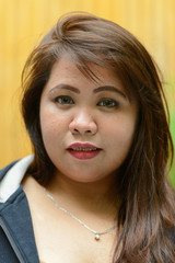 Face of young overweight Asian woman with braces outdoors