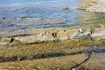 Rocky coast of Black Sea in village of Olginka, Tuapse district. Steep rocky slopes are composed of natural textures. Close-up. Fragments of rock of various sizes go into depths of sea.