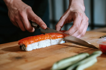 Making sushi and rolls at home. Closeup of a man’s hand