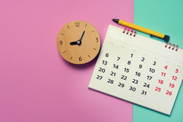 close up of calendar and clock on pink and green the table, planning for business meeting or travel...