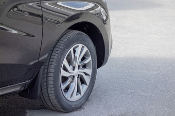 Front wheel on a rim close-up on a new gray crossover in drops after rain.