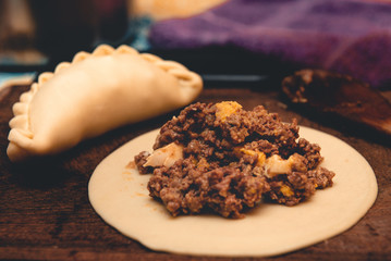 La tradicional empanada de carne argentina, sus ingredientes,  como primer plano sobre una tabla de madera rústica.