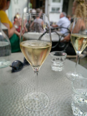 two glasses of champagne on table with glasses and people in the background