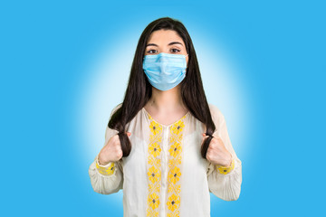 Portrait of young woman wearing a face protective mask isolated on blue background. Protection...