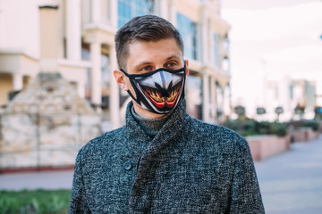 A handsome young man in a black mask  with stylish pattern for protection from coronavirus infection - 342416820