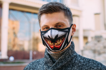 A handsome young man in a black mask  with stylish pattern for protection from coronavirus infection - 342416865